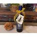 A bottle of wine with a handmade birch bark gift tag tied to the bottle with a yellow bow.